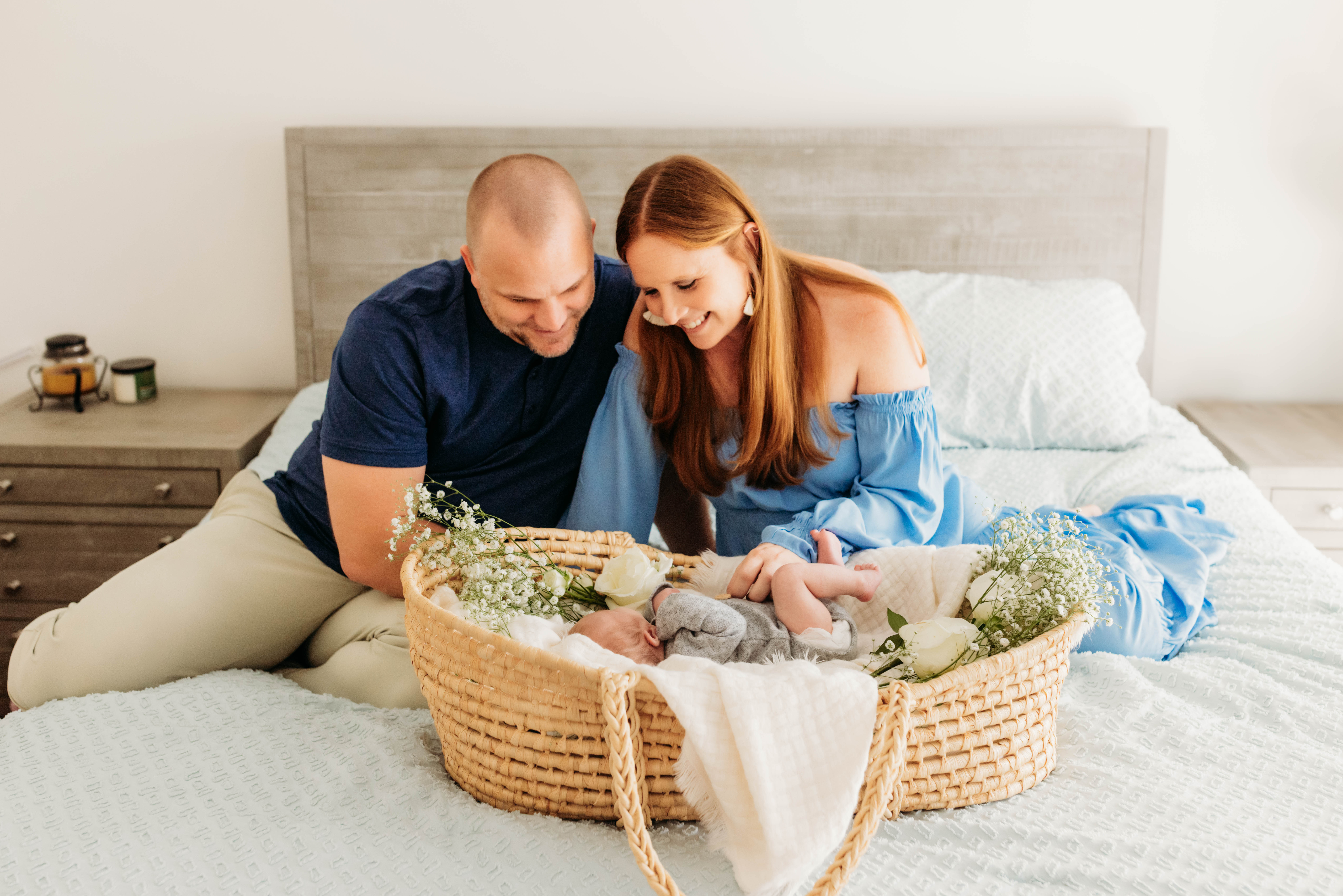 Family looking at newborn baby in moses basket with color coordinated outfits